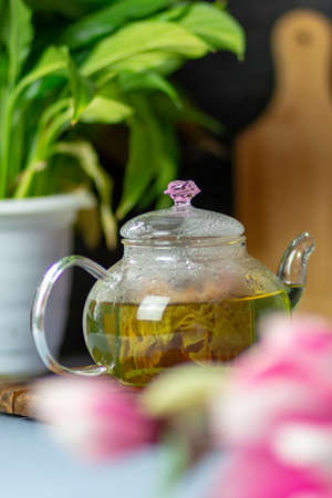 green tea with rose petals in a transparent teapot on a wooden table on a black background. The background is blurred. Tea drinkingの写真素材