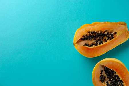 Summer composition. Tropical papaya fruits cut in half lie on a blue background. Summer concept. Flat lay, top view, copy space.の写真素材