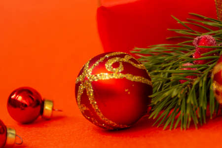 Christmas festive red balls with a gold pattern with a branch of a Christmas tree, on a red background, place for text, close up.の写真素材