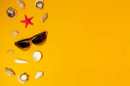 Top view tropical summer background. Sunglasses with starfish, seashells on a yellow background. summer travel concept. Flat lay with copy space.の写真素材