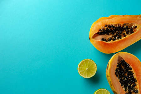 Summer composition. Tropical lime and papaya fruit cut in half lie on a blue background. Summer concept. Flat lay, top view, copy space.の写真素材
