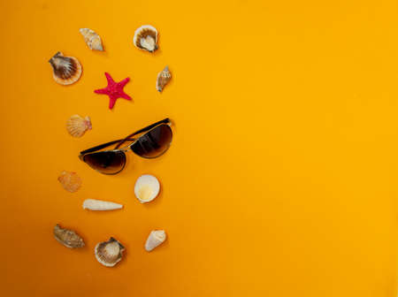 Top view tropical summer background. Sunglasses with starfish, seashells on a yellow background. summer travel concept. Flat lay with copy space.の写真素材