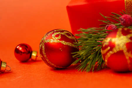 Christmas festive red balls with a gold pattern with a branch of a Christmas tree, on a red background, place for text, close up.の写真素材