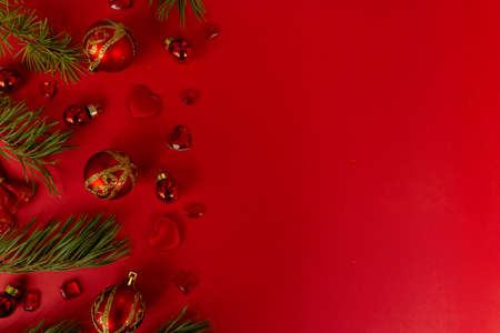 Christmas composition. Christmas red decorations, fir tree branches on red background. Flat lay, top view, copy space.の写真素材