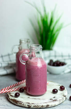 A bottle of cherry smoothies on a white background, cherries in bulk and in a plate. Morning summer breakfastの写真素材