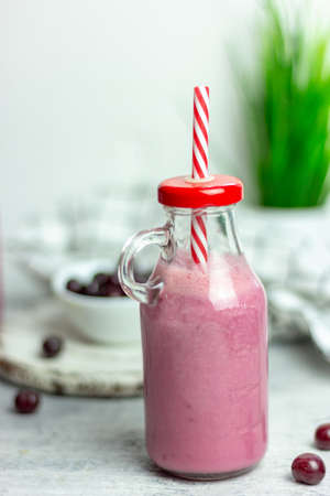 A bottle of cherry smoothies on a white background, cherries in bulk and in a plate. Morning summer breakfastの写真素材