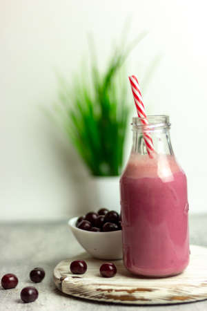 A bottle of cherry smoothies on a white background, cherries in bulk and in a plate. Morning summer breakfastの写真素材