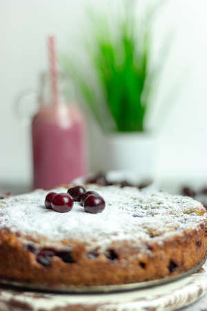 Homemade cherry pie and red cherry smoothie and sprinkled with berries on a gray table, close-up....