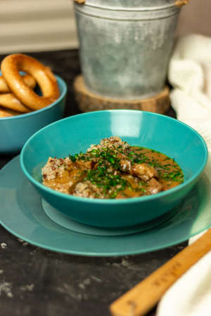 Buckwheat with meat and sauce in a blue plate, sprinkled with herbs. On a dark table. The concept of lunch, or a hearty dinner.の写真素材