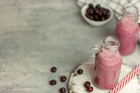 A bottle of cherry smoothies on a white background, cherries in bulk and in a plate. Morning summer breakfastの写真素材