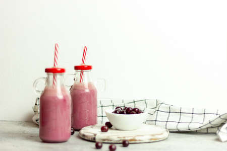 A bottle of cherry smoothies on a white background, cherries in bulk and in a plate. Morning summer breakfastの写真素材