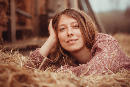 Cute country girl relaxed lying in hay.の写真素材