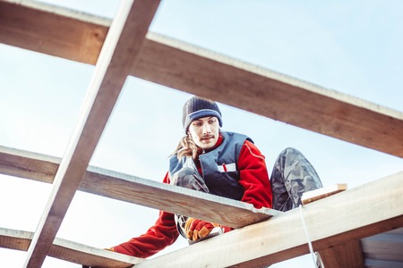 a man in a construction vest sitting on the roofの写真素材