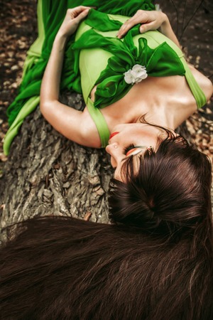 girl lying on a log in the woods in a green dressの写真素材