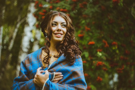 girl standing in the blanket under the red berriesの写真素材