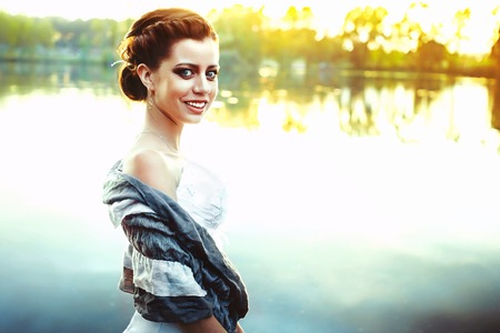 Young Beautiful Sexy Girl standing near the River or Lake and enjoying Peaceful Moment of Absolutely Amazing Sunset in the American Villageの写真素材