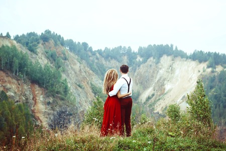 Attractive young loving couple of man in white shirt and with the green mountain landscapeの写真素材