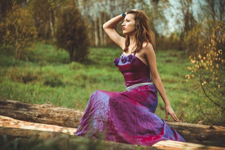 happy girl outdoors in dress sitting on the treeの写真素材