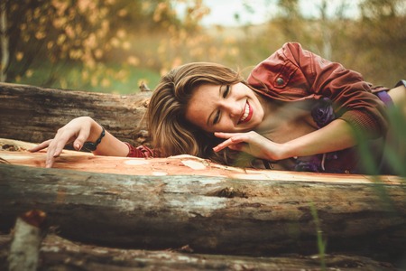 happy girl outdoors in dress sitting on the treeの写真素材