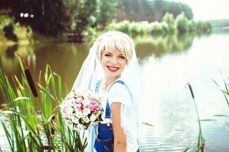 the bride in a veil sitting at the lake in the grassの写真素材