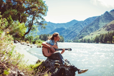 Beautiful hairy man with a guitar on the beachの写真素材