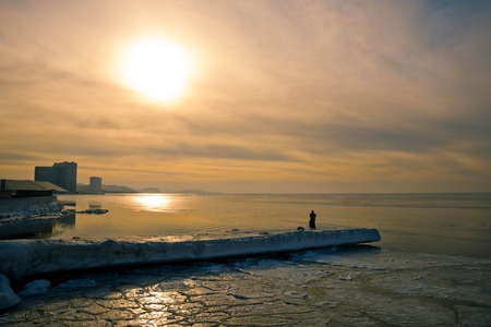 View of snow covered piers on frozen Blue sky, clouds and opposite shore beyond.の写真素材