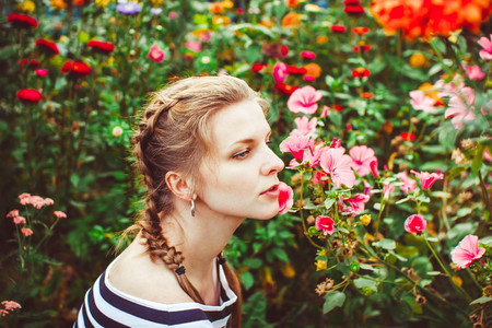 Woman in a summer garden in a dress among flowersの写真素材