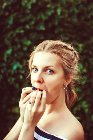 Woman in the summer garden in a dress eating a berryの写真素材