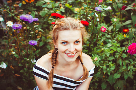 Woman in a summer garden in a dress among flowersの写真素材