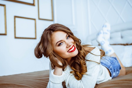 Pretty woman lying down on her bed at homeの写真素材