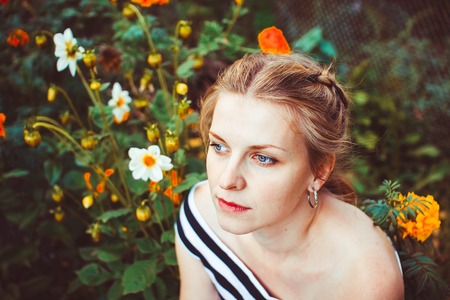 Woman in a summer garden in a dress among flowersの写真素材