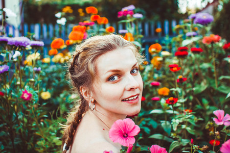 Woman in a summer garden in a dress among flowersの写真素材