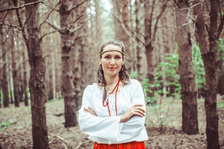 A young woman stands between trees in a forestの写真素材