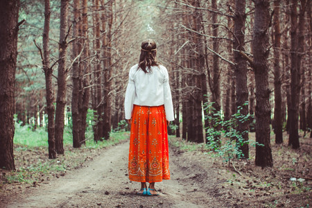A young woman stands between trees in a forestの写真素材