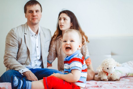 Happy family, mother, father and daughter on the white bedの写真素材