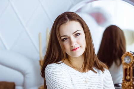 Beautiful woman in the mirror reflected the smiles magically in retro interiorの写真素材