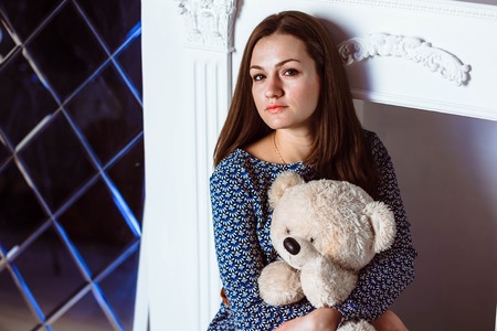 Woman sitting with a toy teddy bearの写真素材