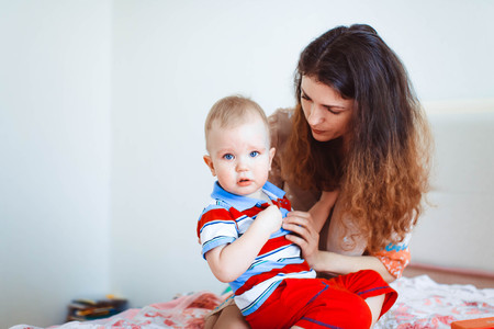 Mom and son are sitting on the bed, sad boyの写真素材