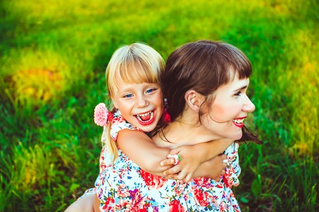 Cute young daughter on a piggy back ride with her mother. Looking at camera.の写真素材