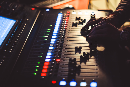 The hands of the sound engineer on the mixing consoleの写真素材