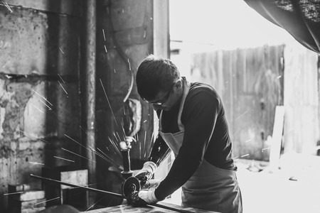 Craftsman sawing metal sparkles all around workshop. Working at noon.の写真素材