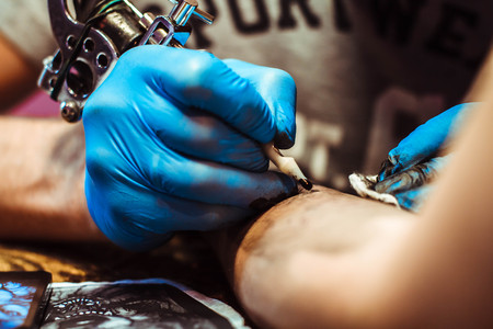 Russia, Novokuzneck, 5.07.2017: The tattoo artist makes a tattoo on the client's neck in the tattoo salon. The master does a tattoo in the studio. Close-up. Hard. Pain.のeditorial素材