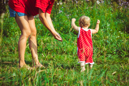 The child learns to walk in the park barefoot on the grassの写真素材