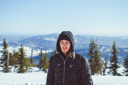 The mountaineer pointing at peak, standing against a winter mountain landscape.の写真素材