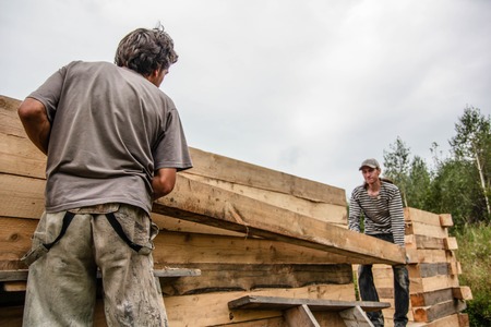 Russia, Siberiya - 1.09.2013: Construction worker framing the roof of a country house with help of a craneのeditorial素材