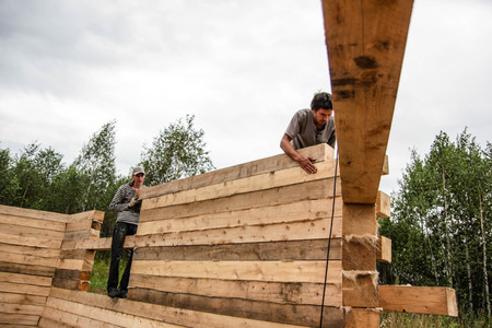 Russia, Siberiya - 1.09.2013: Construction worker framing the roof of a country house with help of a craneのeditorial素材