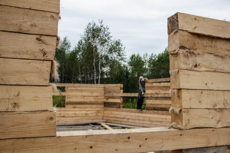 Russia, Siberiya - 1.09.2013: Construction worker framing the roof of a country house with help of a craneのeditorial素材