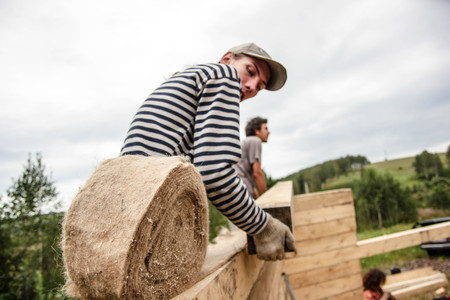 Russia, Siberiya - 1.09.2013: Construction worker framing the roof of a country house with help of a craneのeditorial素材