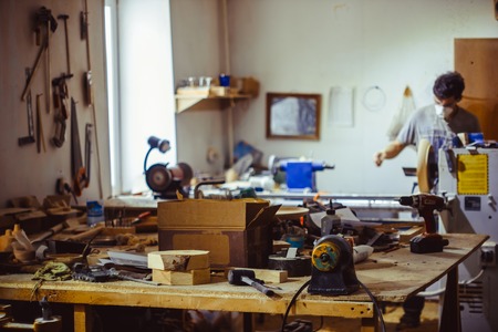 Leather crafting tools on working desk with the scratches. Blurred background of leather workshop. Copy space.の写真素材