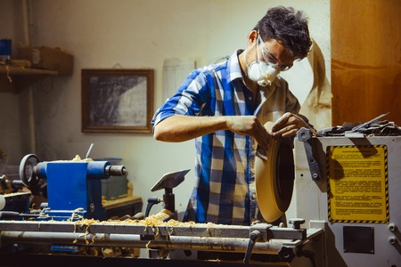 man turning a wooden plate on a latheの写真素材